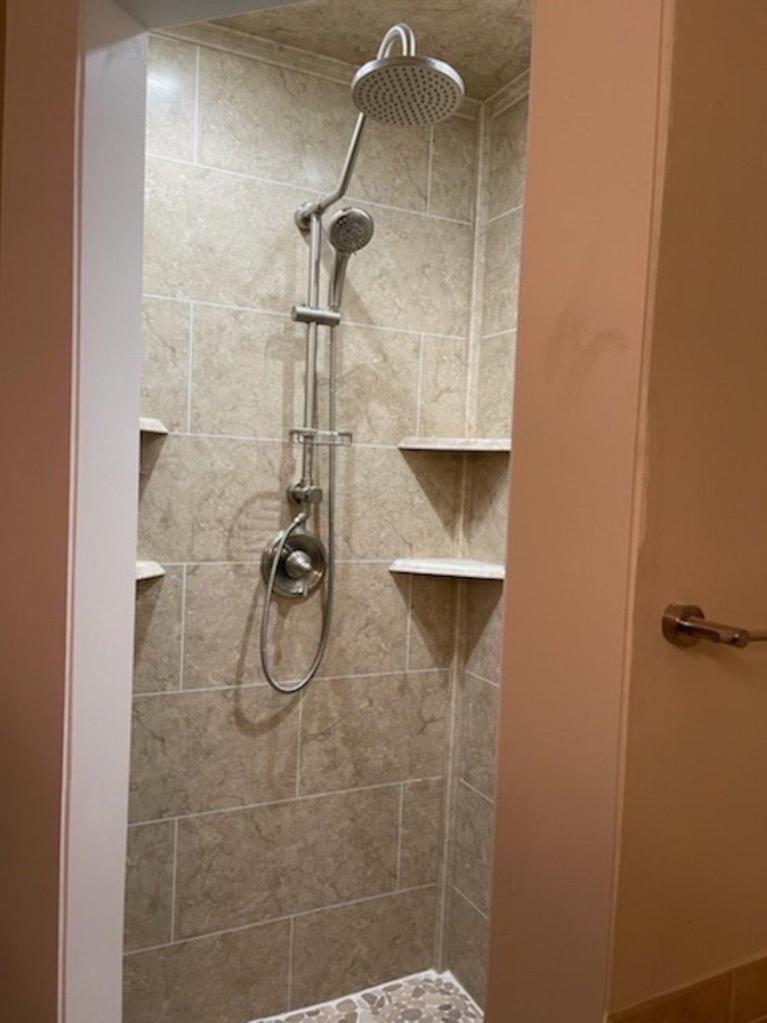 White bathtub with a refreshed stone-look tile surround and corner shelves